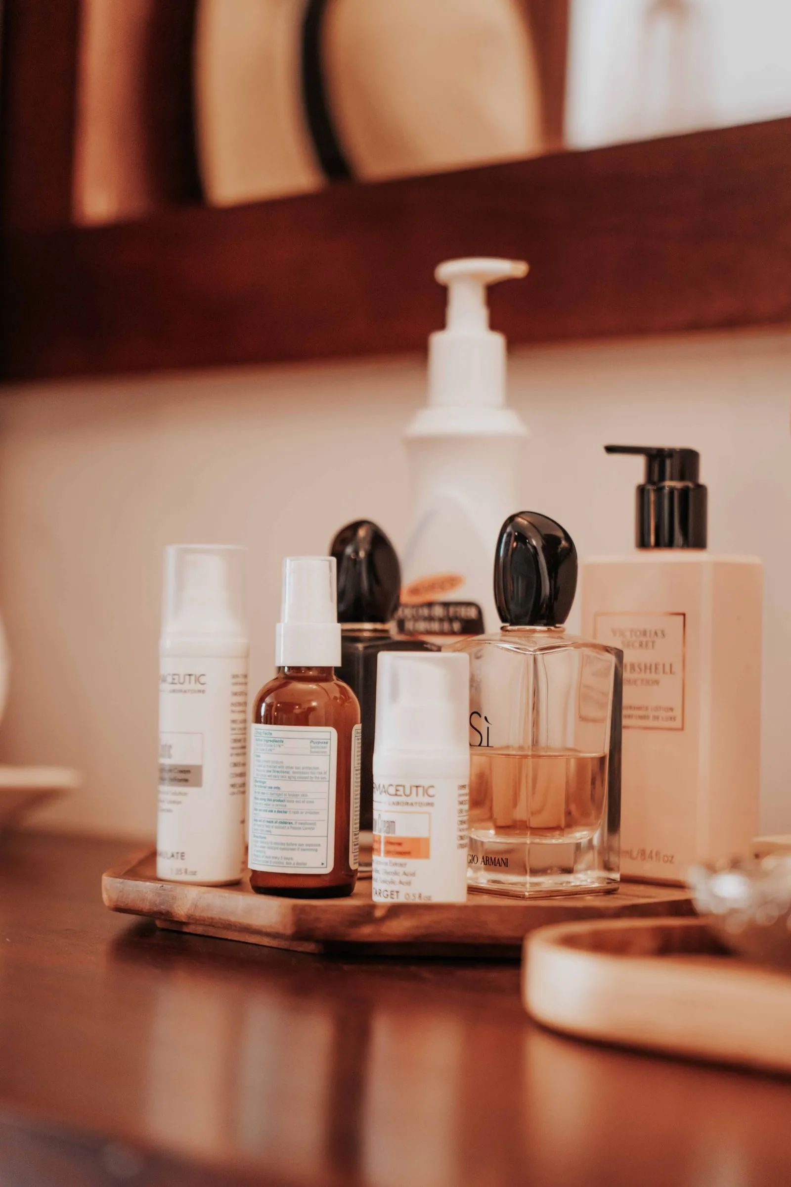 Cosmetic bottles arranged neatly on a wooden tray in a bathroom setting