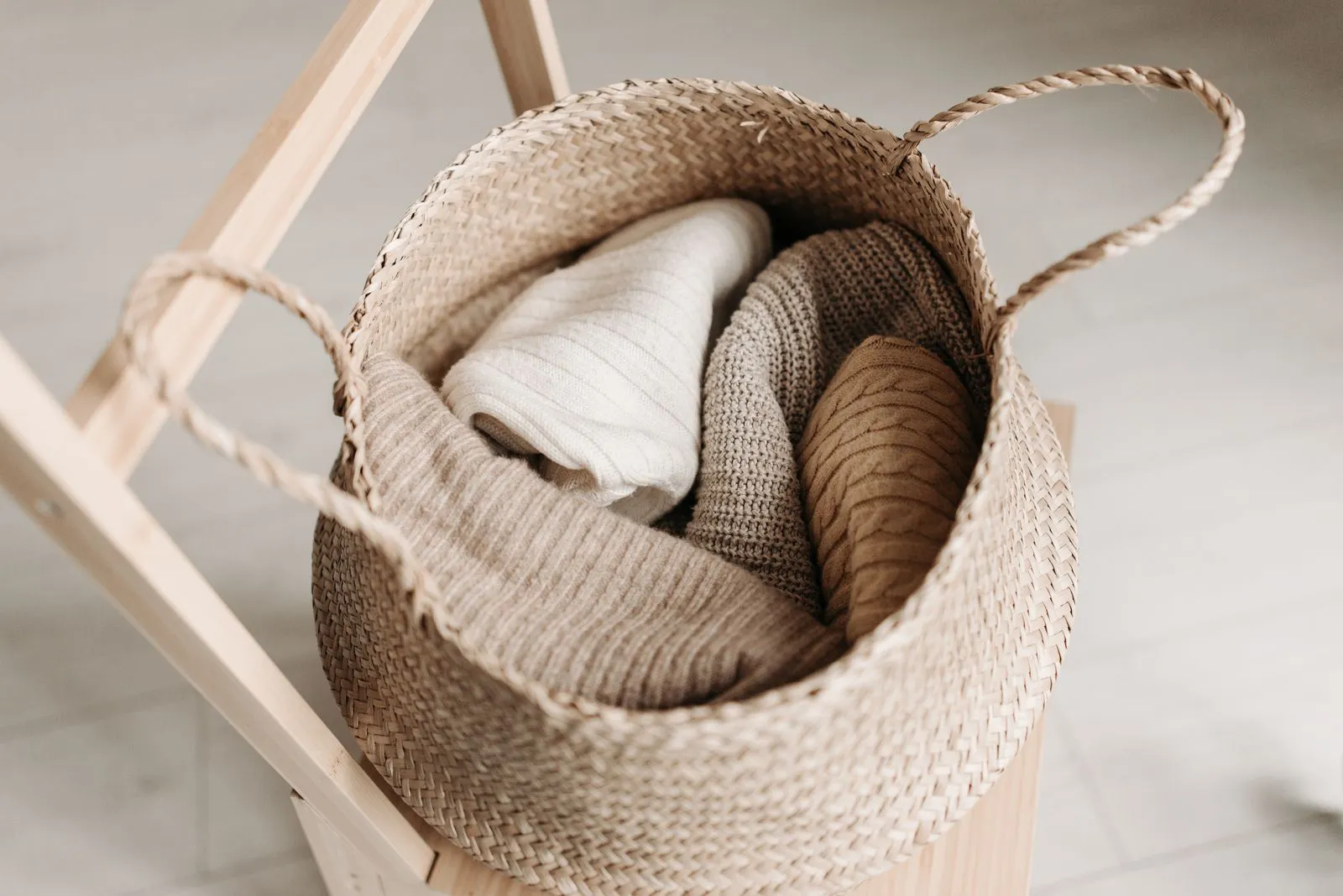 Woven storage basket filled with several neatly folded knit sweaters