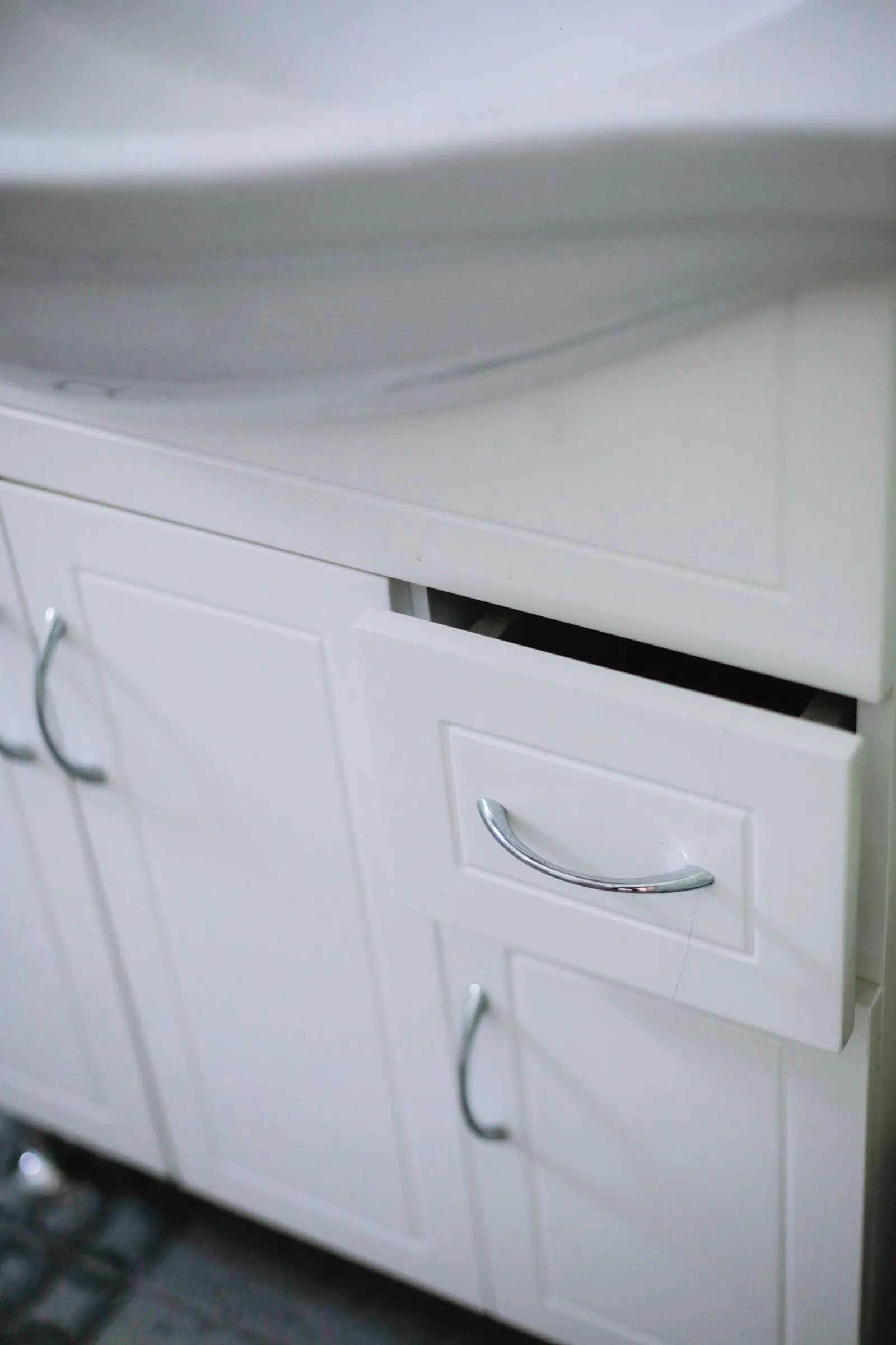 Close-up of a sleek white bathroom cabinet with a drawer beside the sink