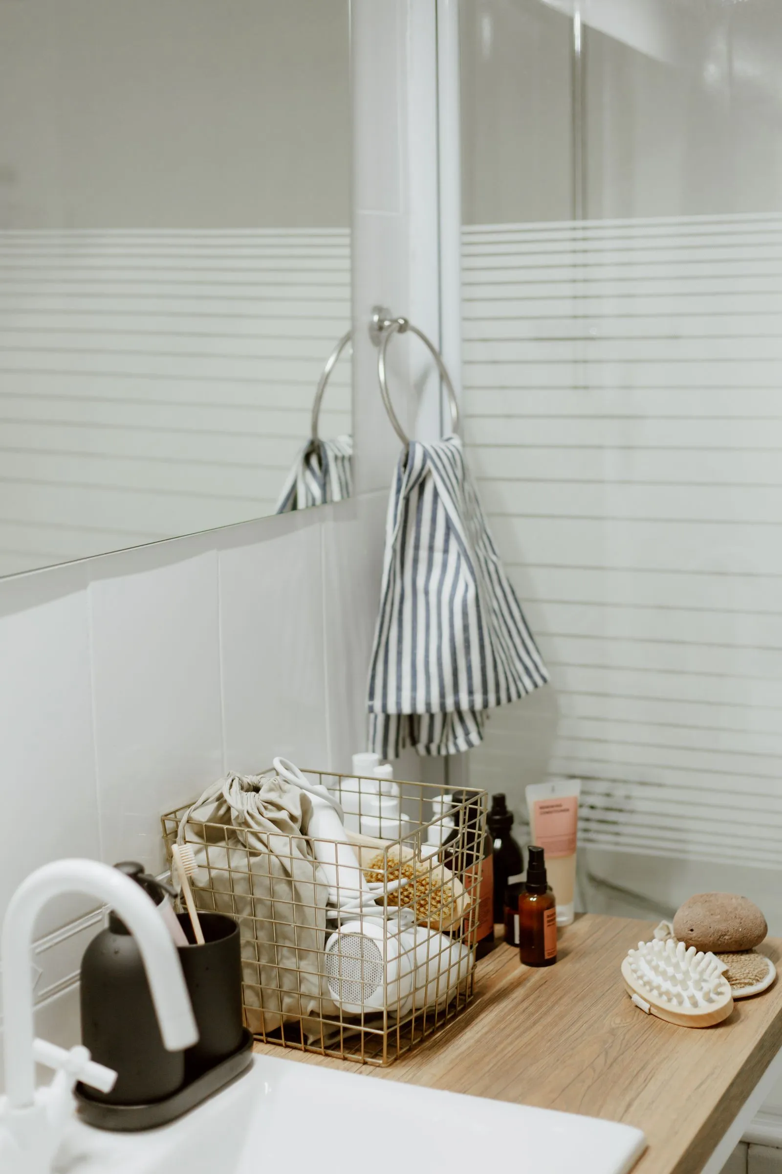 An elegant bathroom vanity with a modern faucet, organized skincare products, and a neatly arranged basket