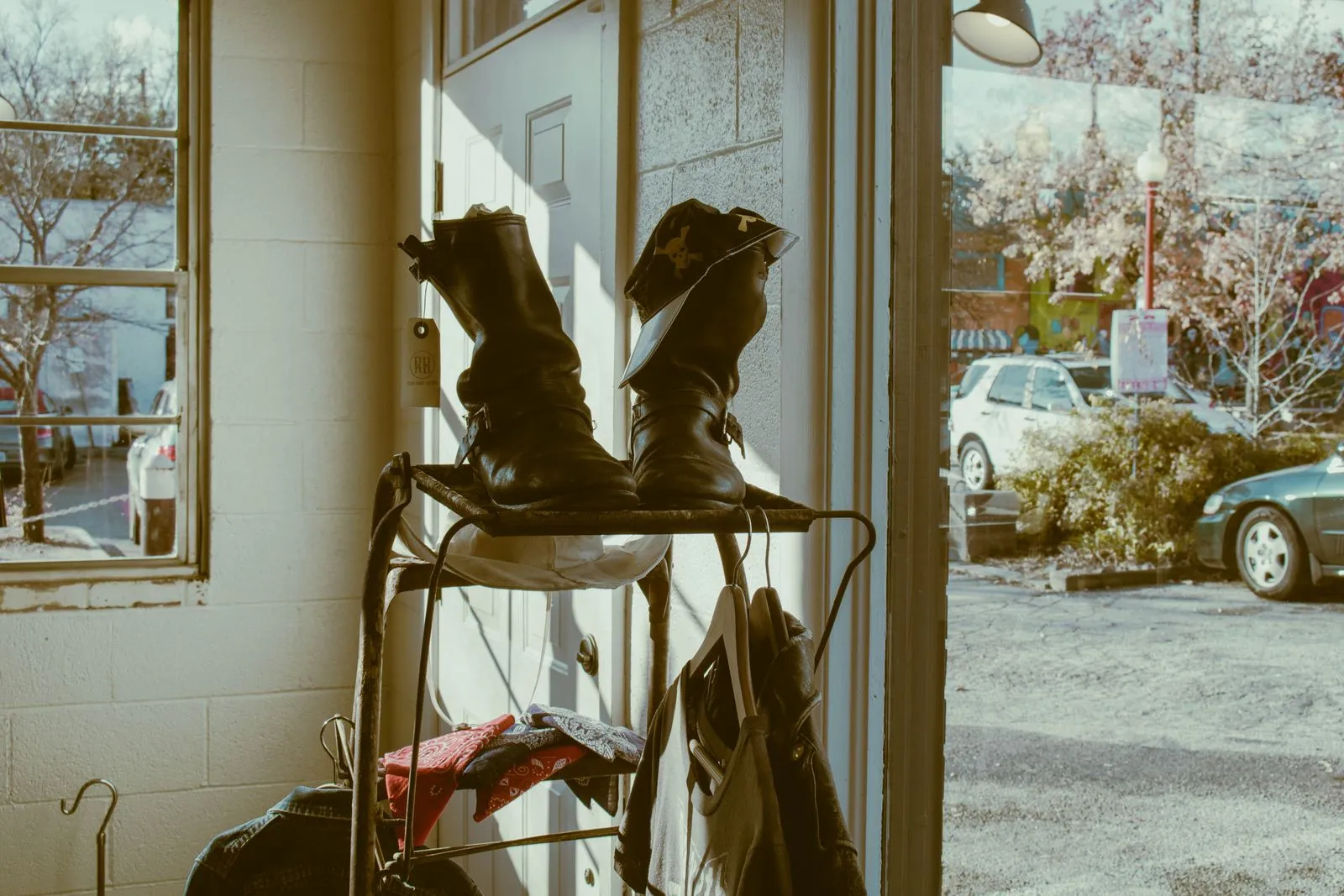 Vintage brown leather boots displayed on a rack near a sunlit entryway doorway