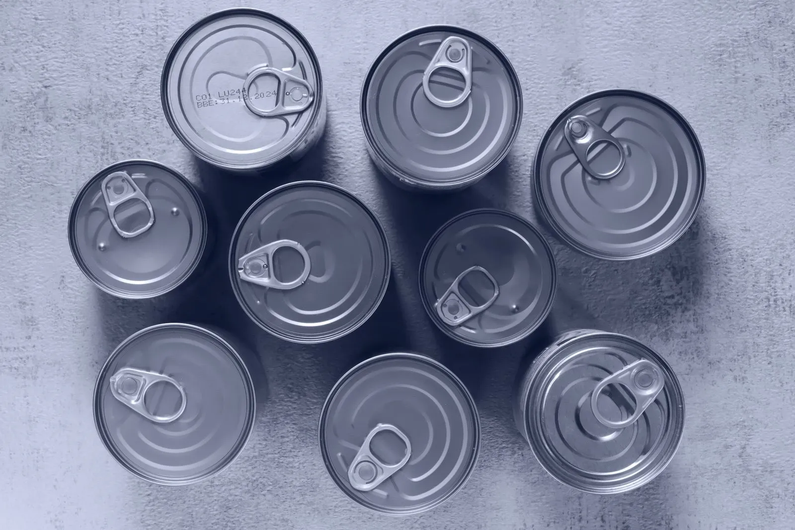 Overhead view of several unlabeled food cans with pull-tab lids grouped together